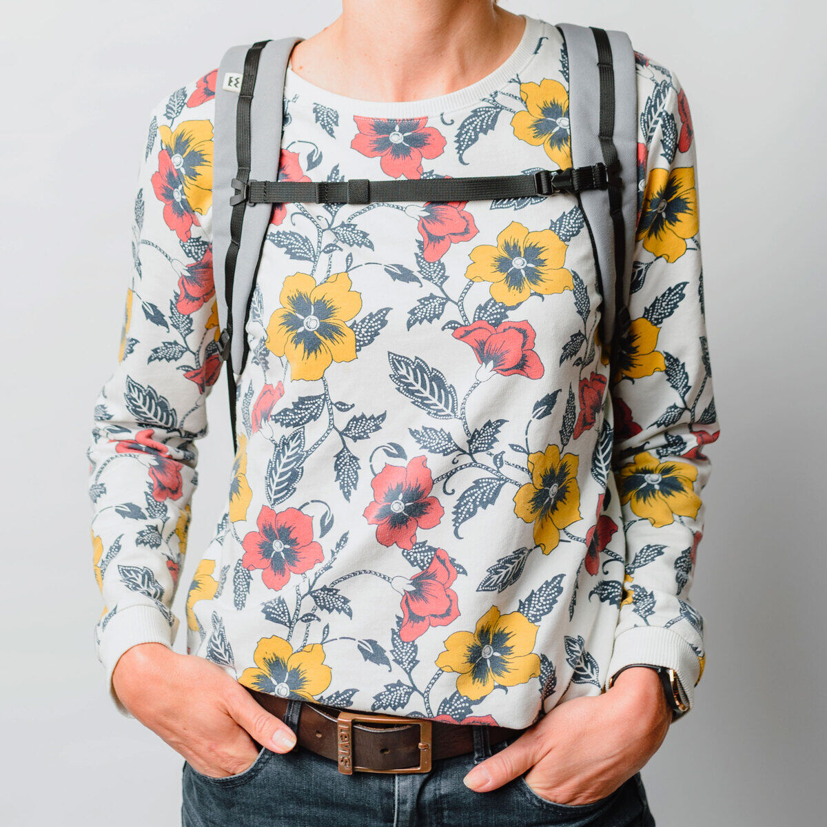 Eine Person trägt einen grau-schwarzen Fahrradtasche/Rucksack »Annecy« vor einem hellen Hintergrund. Der Rucksack hat eine moderne und stilvolle Gestaltung und ist auf Funktionalität ausgerichtet.
