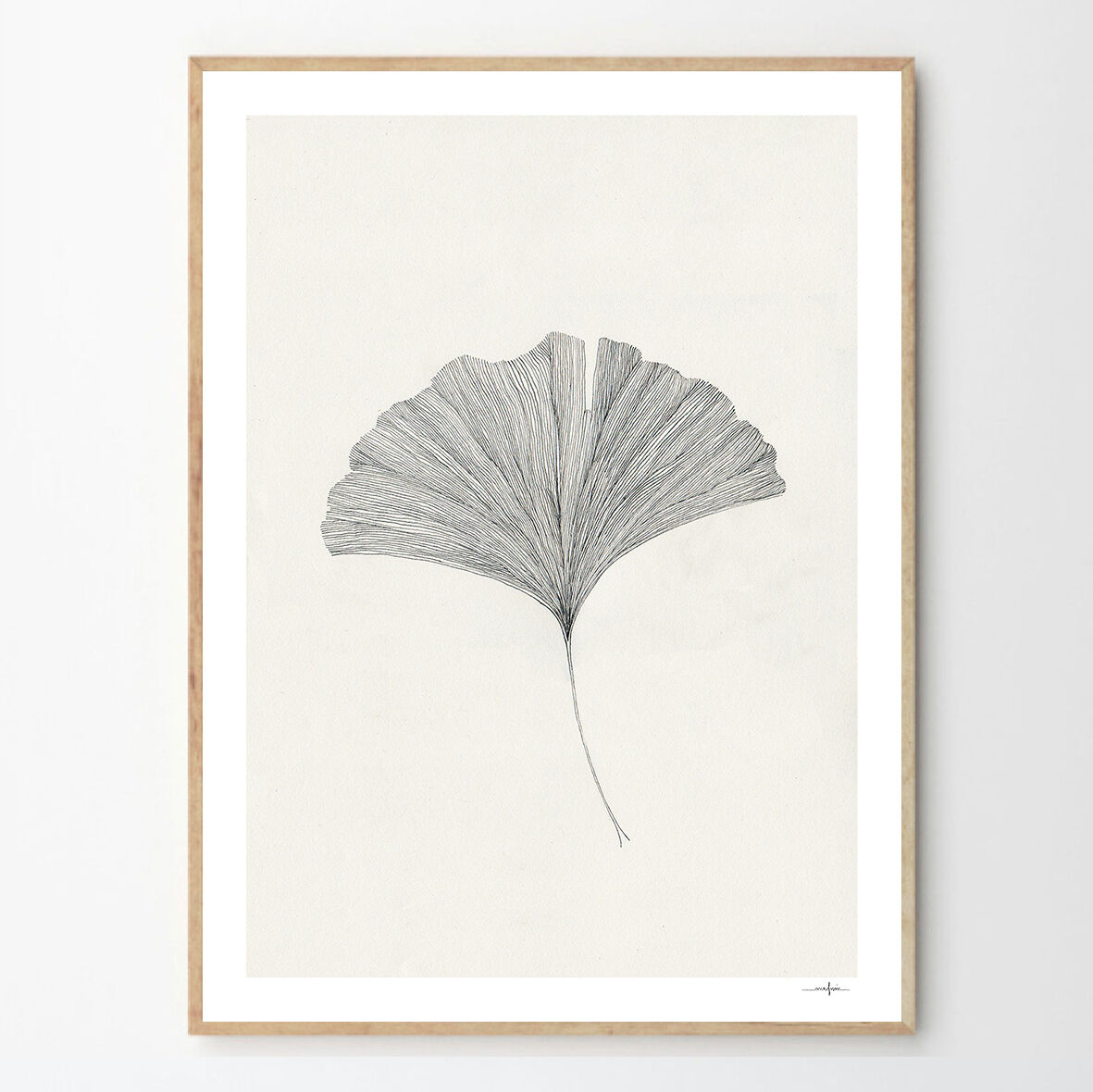 Ein minimalistisch gerahmter Kunstdruck zeigt ein Ginkgoblatt in Schwarz-Weiß. Das Blatt ist zentral auf einem hellen Hintergrund platziert, umgeben von einem schlichten Holzrahmen.