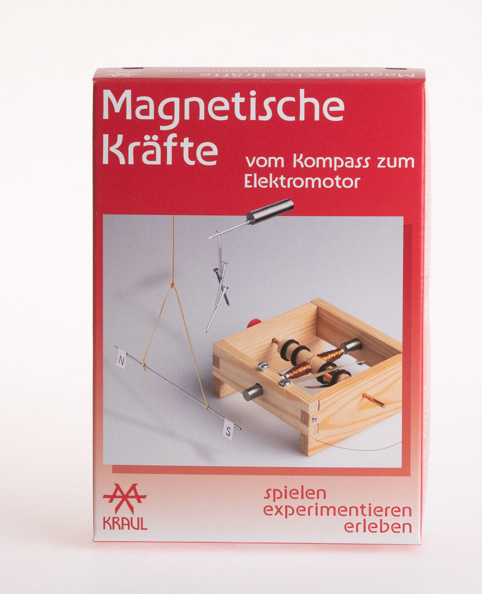 Experimentierkasten 'Magnetische Kräfte' von Kraul. Das Bild zeigt den Bausatz, der von einem Holzrahmen, Magneten und elektrische Komponenten besteht. Auf der Verpackung ist der Text 'Magnetische Kräfte - vom Kompass zum Elektromotor' in Weiß vor rotem Hintergrund zu sehen.