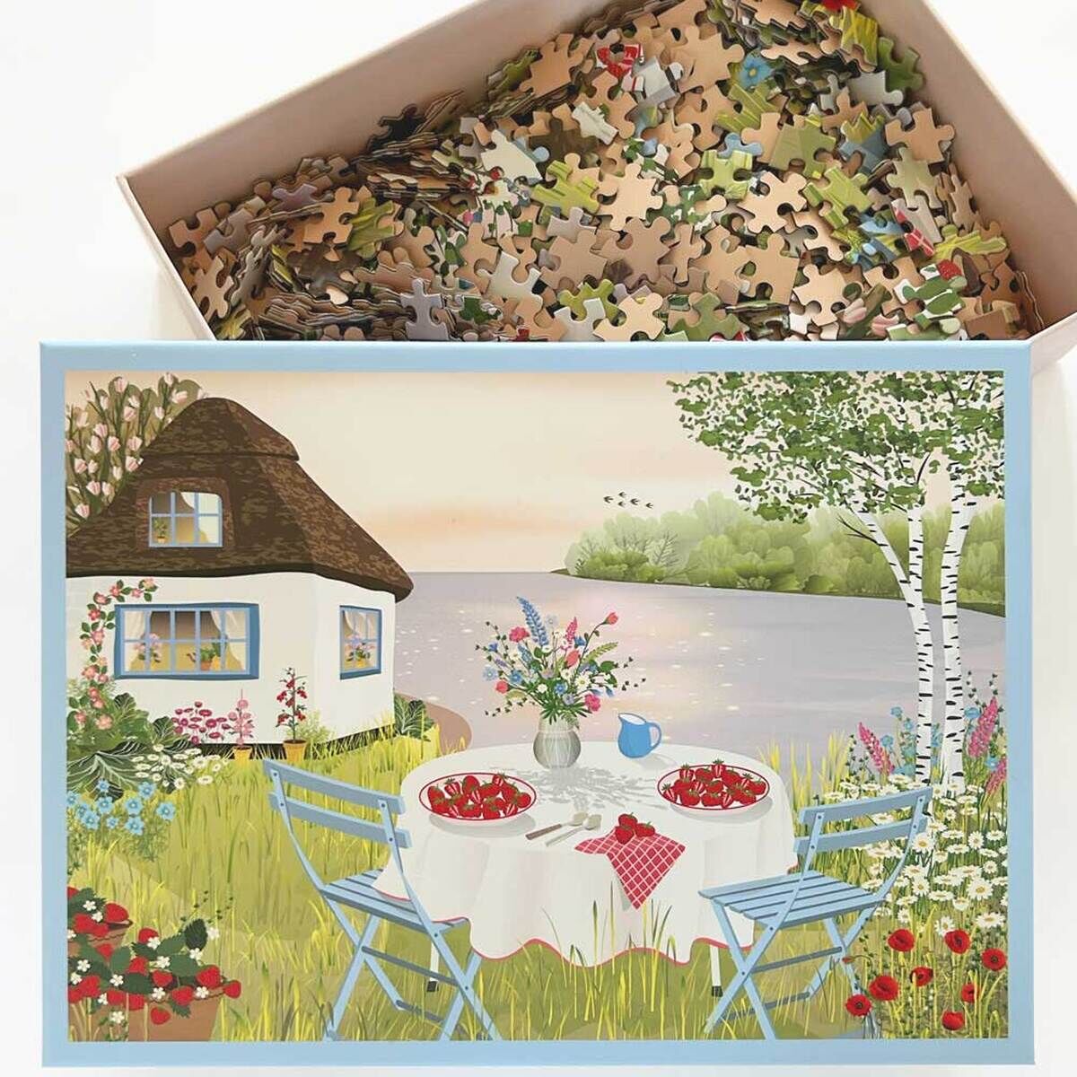Ein Puzzle mit einem Bild von einem gedeckten Tisch im Garten neben einem See. Auf dem Tisch stehen Erdbeeren und ein Blumenstrauß. Im Hintergrund ist ein Haus zu sehen, umgeben von Blumen und Bäumen.