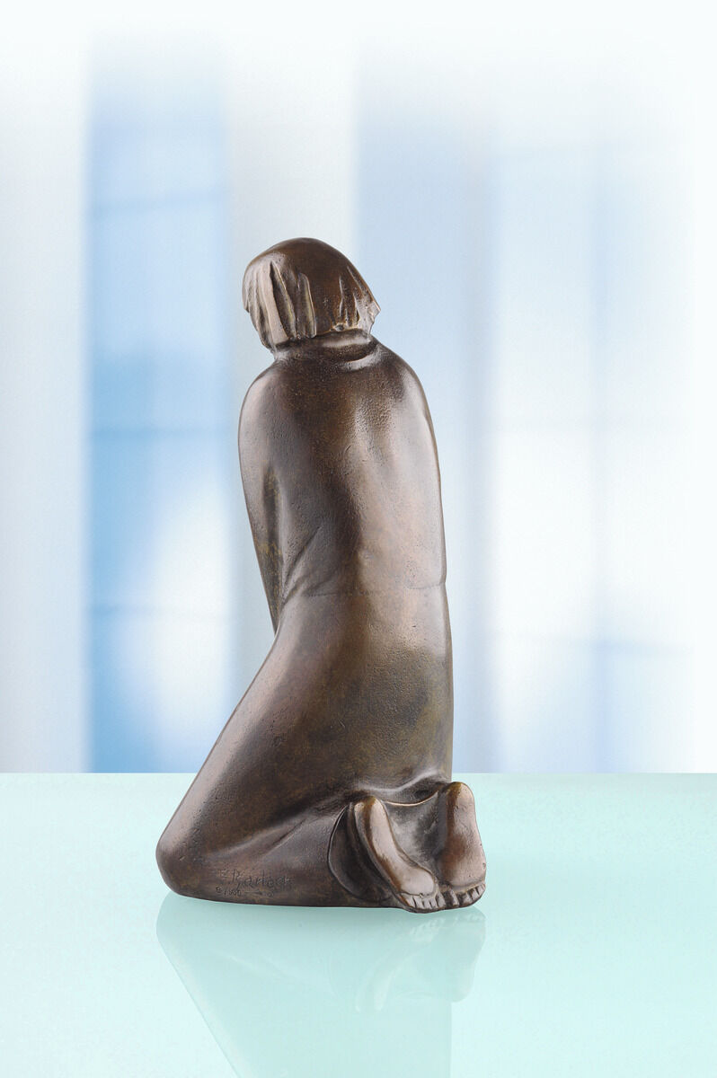 Die Bronzeskulptur 'Der Zweifler' von Ernst Barlach aus dem Jahr 1931 zeigt eine Figur, die in einer nachdenklichen Haltung kniet. Die Figur ist in Bronze gehalten und hat eine braune Farbgebung. Der Hintergrund ist durch weiche Blau- und Grüntöne gekennzeichnet.