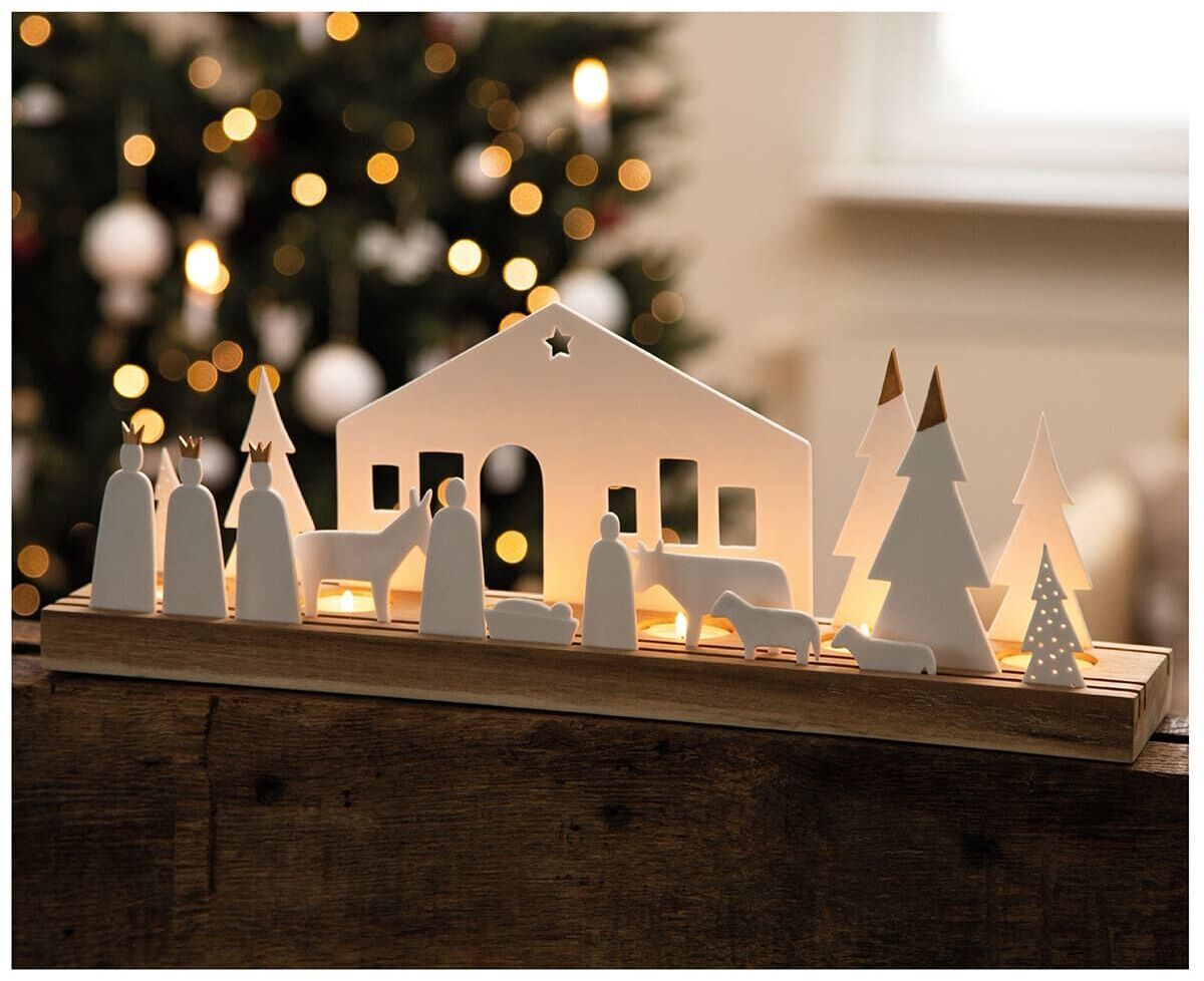 Eine dekorative Weihnachtskrippe aus Holz mit LED-Beleuchtung. Die Szenerie zeigt eine einfache Krippe mit Figuren, darunter Maria, Josef, das Jesuskind und verschiedene Tiere, vor einem unscharfen Hintergrund mit Weihnachtsbaum und Lichtern.