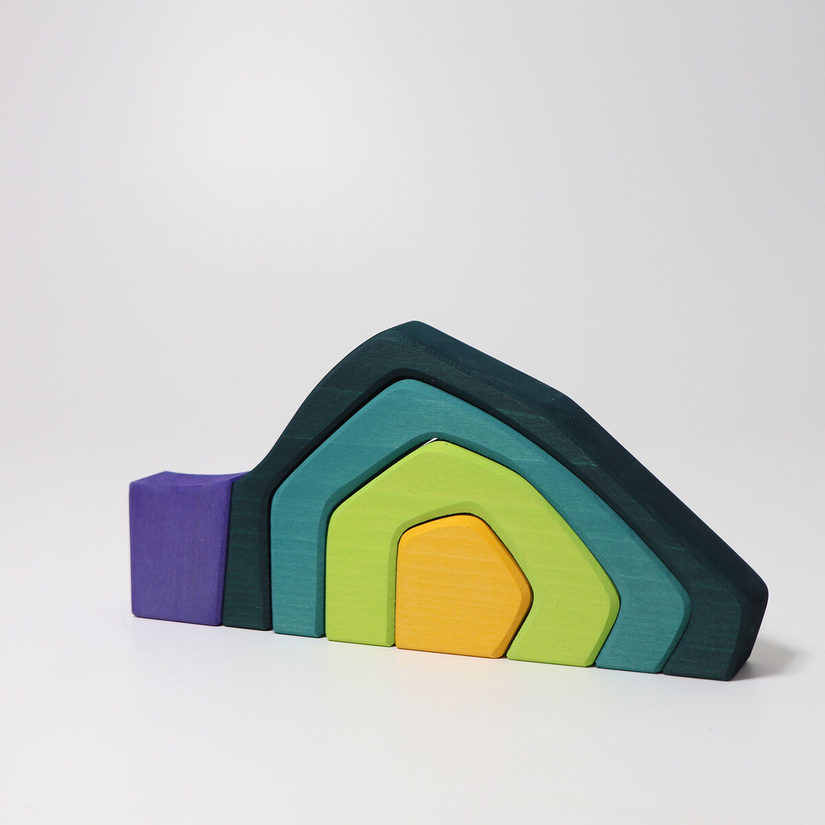 Das Bild zeigt einen bunten Baukasten aus Holz mit verschiedenen ineinander passenden Formen in den Farben Blau, Grün, Gelb und Lila. Es ist das Spielzeug 'Vier Elemente Baukasten.'