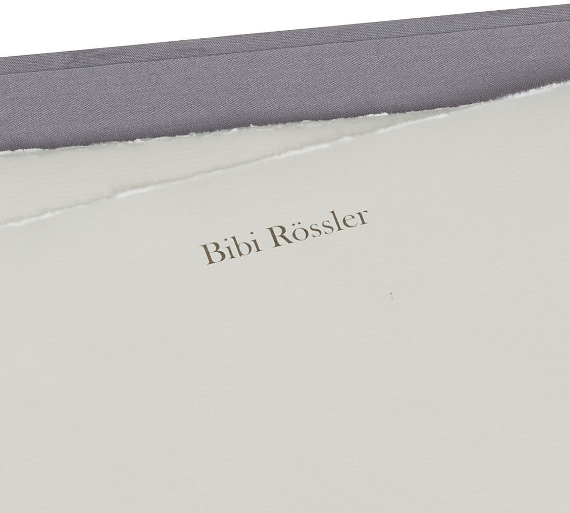 Hochwertige Briepapiermappe mit edlem Büttenpapier in einem eleganten Grauton. Das Papier hat abgerissene Kanten und trägt den Namen 'Bibi Rössler'.