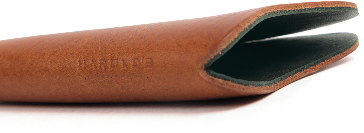 Kernleder Brillenetui in Cognacbraun, seitlich liegend. Glatte, hochwertige Lederschale mit dunklerem grünem Innenfutter, schlankes und minimalistisches Design, ideal zur stilvollen Aufbewahrung von Brillen, für designaffine Brillenträger geeignet.