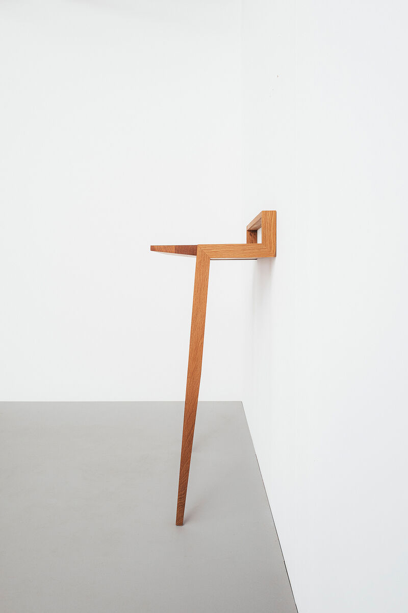 Ein minimalistisches Stehpult aus Holz, das platzsparend an eine weiße Wand montiert ist. Es hat eine schlichte, aber funktionale Bauweise mit klaren Linien und einer natürlichen Holzoptik.
