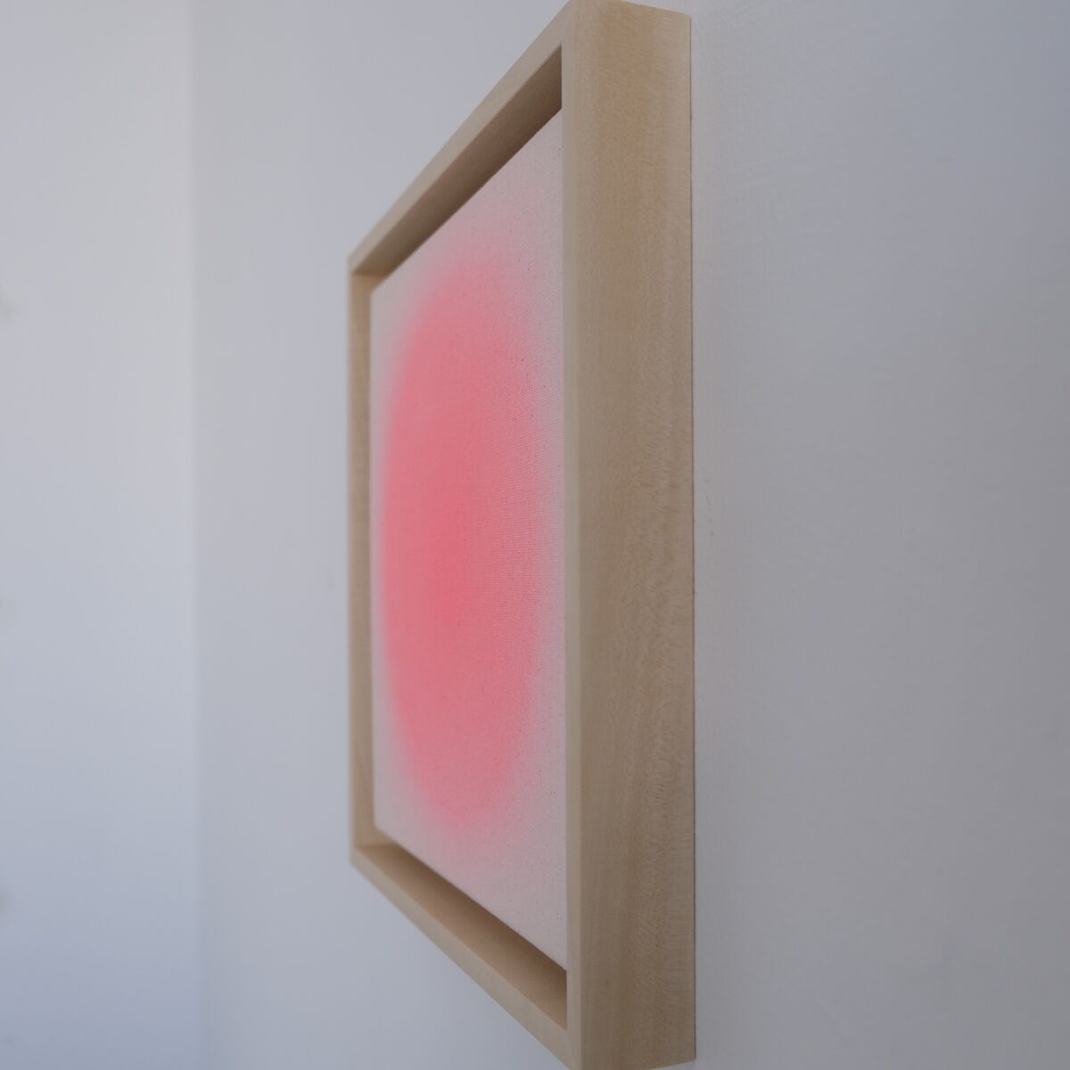 Seitlich aufgenommenes Kunstwerk ZEIT-Sonderedition Sorbet »Rot« im Format 25x25cm, das einen sanften roten Farbverlauf auf weißem Hintergrund innerhalb eines hellen Holzrahmens zeigt. Das Werk hängt an einer weißen Wand und hebt die minimalistische, moderne Ästhetik hervor.