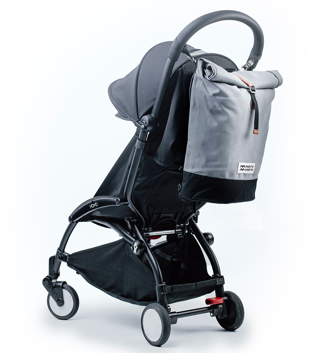 Ein eleganter grauer Rucksack „Wanaka“, der an einem schwarzen Kinderwagen befestigt ist. Der Rucksack hat ein minimalistisches Design und eine hohe Funktionalität, ideal für Eltern und unterwegs.