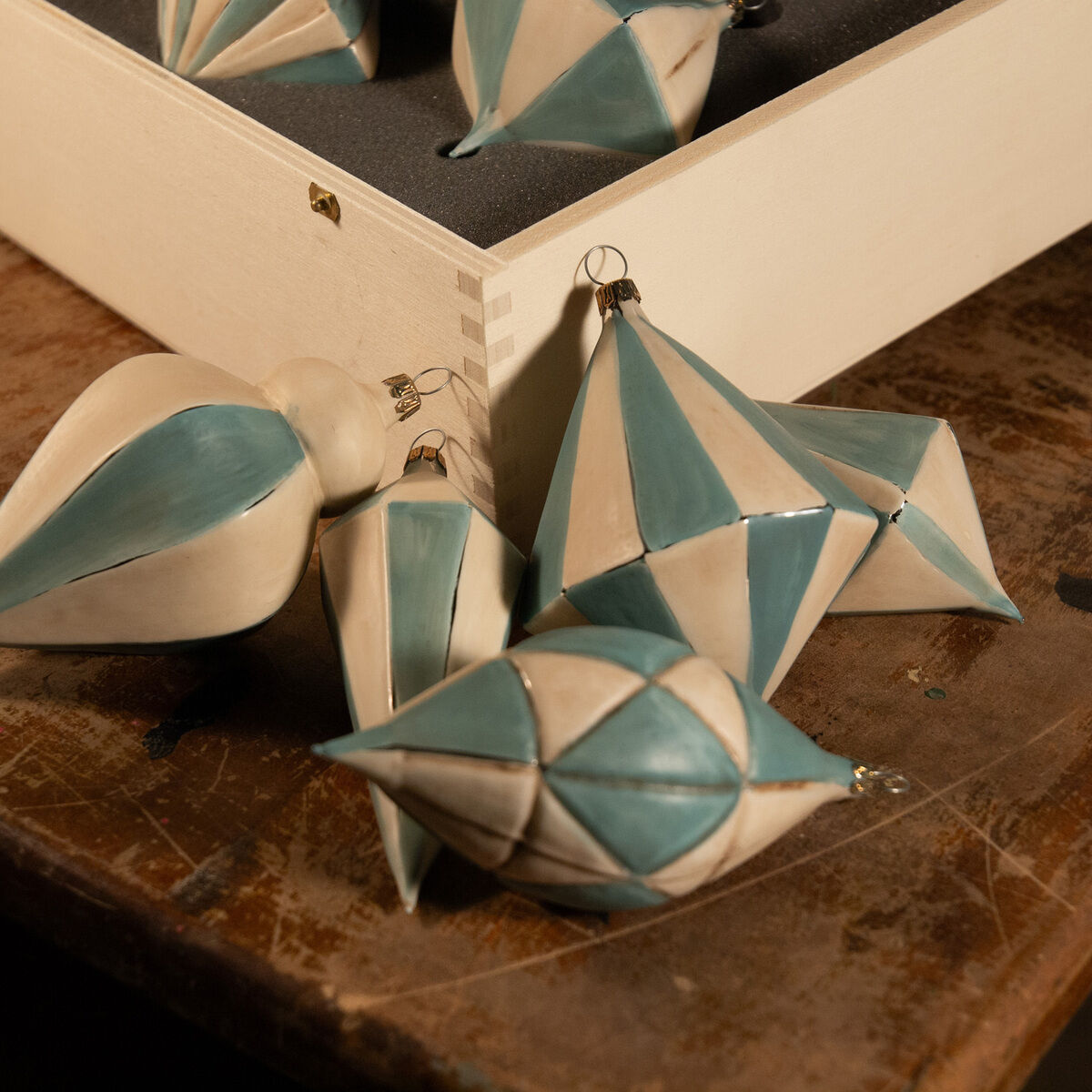 Ein Set von zehn Christbaumkugeln in verschiedenen Formen, hauptsächlich in Weiß und Hellblau, auf einem Holzuntergrund. Ideal für die Weihnachtsdekoration.