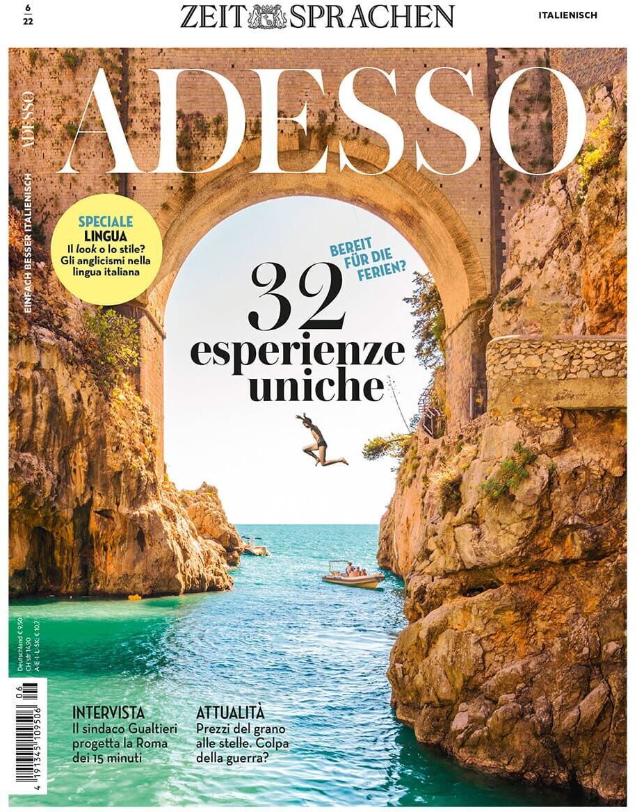 Das Cover der Adesso Ausgabe 06/2022 zeigt eine malerische Landschaftsszene mit einer Brücke, türkisfarbenem Wasser und Felsen. Im Hintergrund springt eine Person ins Wasser und ein Boot gleitet über das Meer. Oben steht der Titel 'Adesso' in großen Buchstaben.