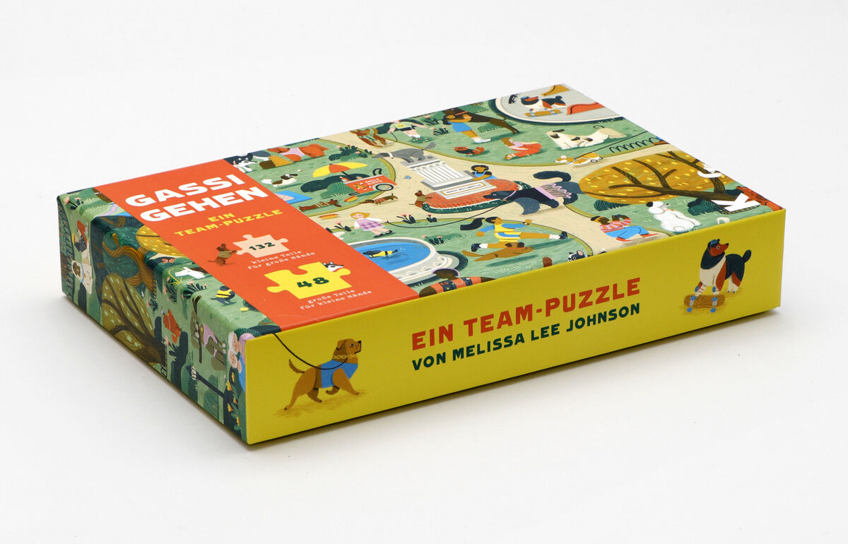 Eine Puzzle-Box mit dem Titel 'Gassi gehen'. Die Verpackung zeigt eine bunte Illustration von Menschen und Hunden, die in einem Park spazieren gehen. Das Puzzle umfasst 48 Teile und wird als Team-Puzzle beworben.