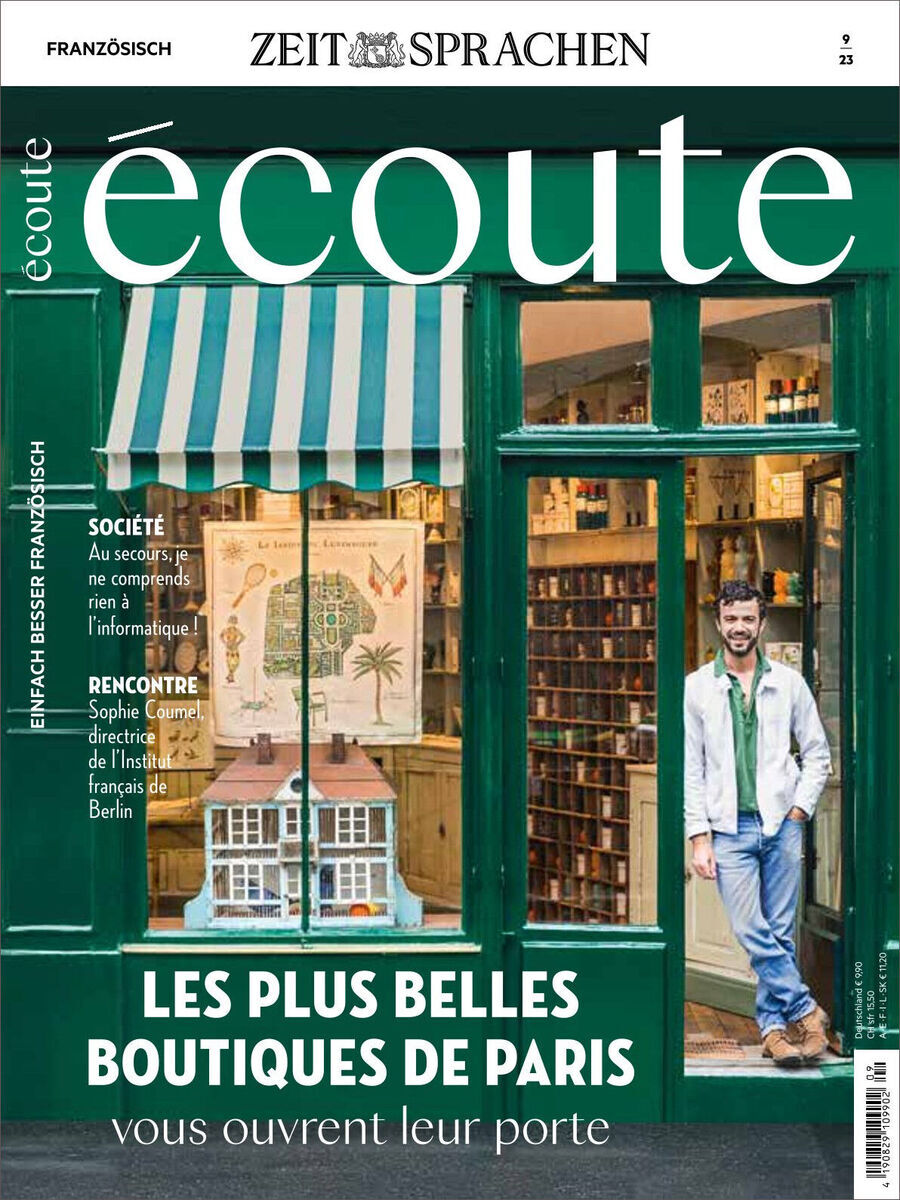 Cover der Ausgabe 09/2023 des Écoute Magazins. Das Bild zeigt eine Ladenfront mit grün gestrichenen Holzrahmen und einem Schaufenster, hinter dem im Detail eine Miniaturausstellung einer anderen Ladenfront zu sehen ist. An der Tür steht ein Mann in einem blauen Hemd und weißem Mantel. Über dem Bildtext befindet sich der Titel 'Écoute' in großer, grüner Schrift.