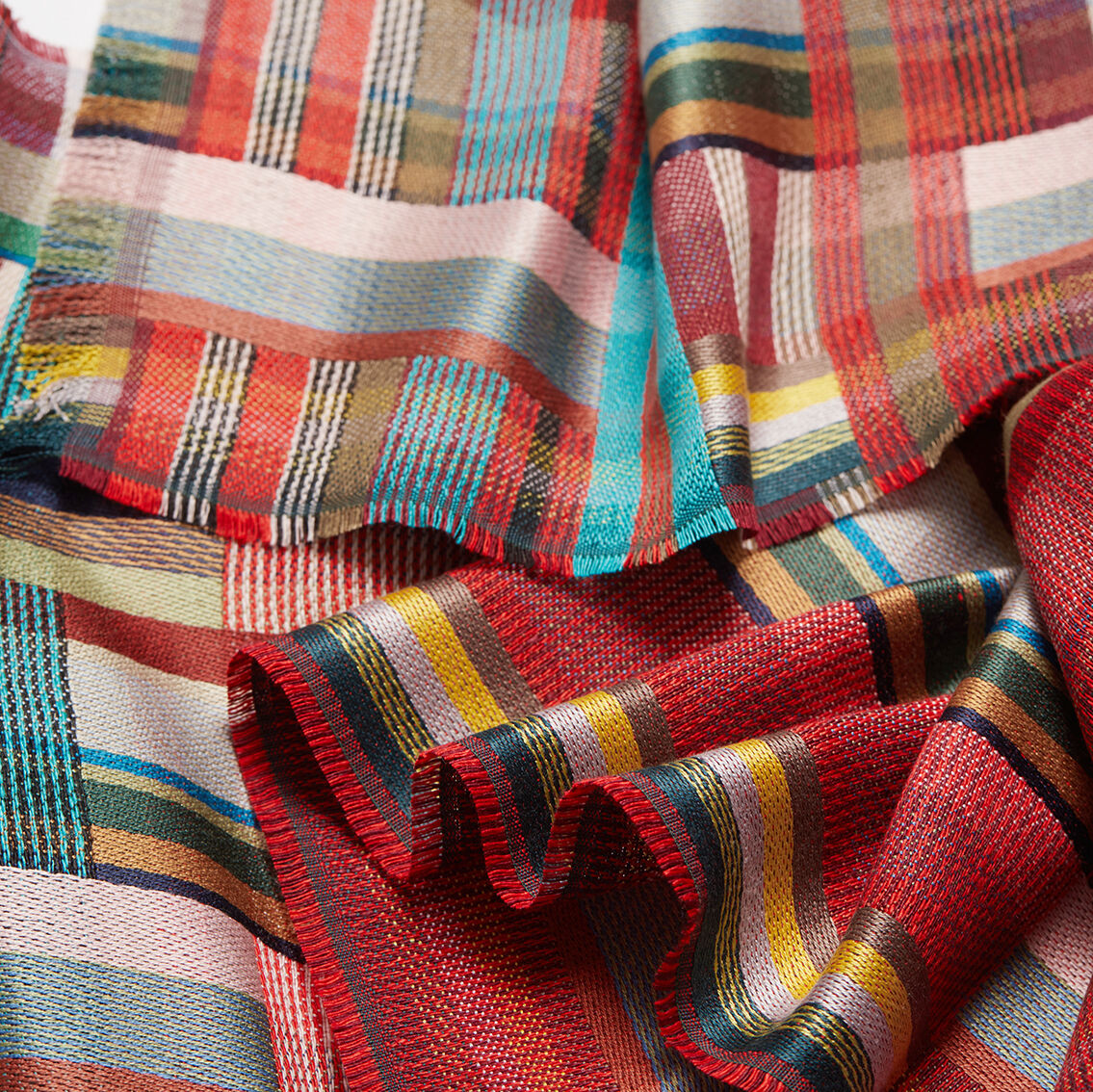 Ein bunter Seide-Leinen-Schal mit Streifenmuster in verschiedenen Farben, einschließlich Rot, Blau, Grün, Gelb, Beige und Türkis. Der Schal ist auf einer Fläche ausgebreitet und zeigt seine leichte und weiche Struktur.