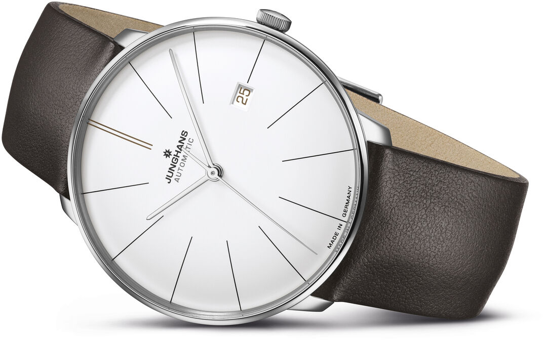 Die ZEIT-Sonderedition „Meister fein Automatic“ von Junghans ist eine elegante Armbanduhr mit einem schlichten weißen Zifferblatt. Sie verfügt über ein schwarzes Lederarmband und ein Datum auf der rechten Seite. Gehäuse aus poliertem Silber.