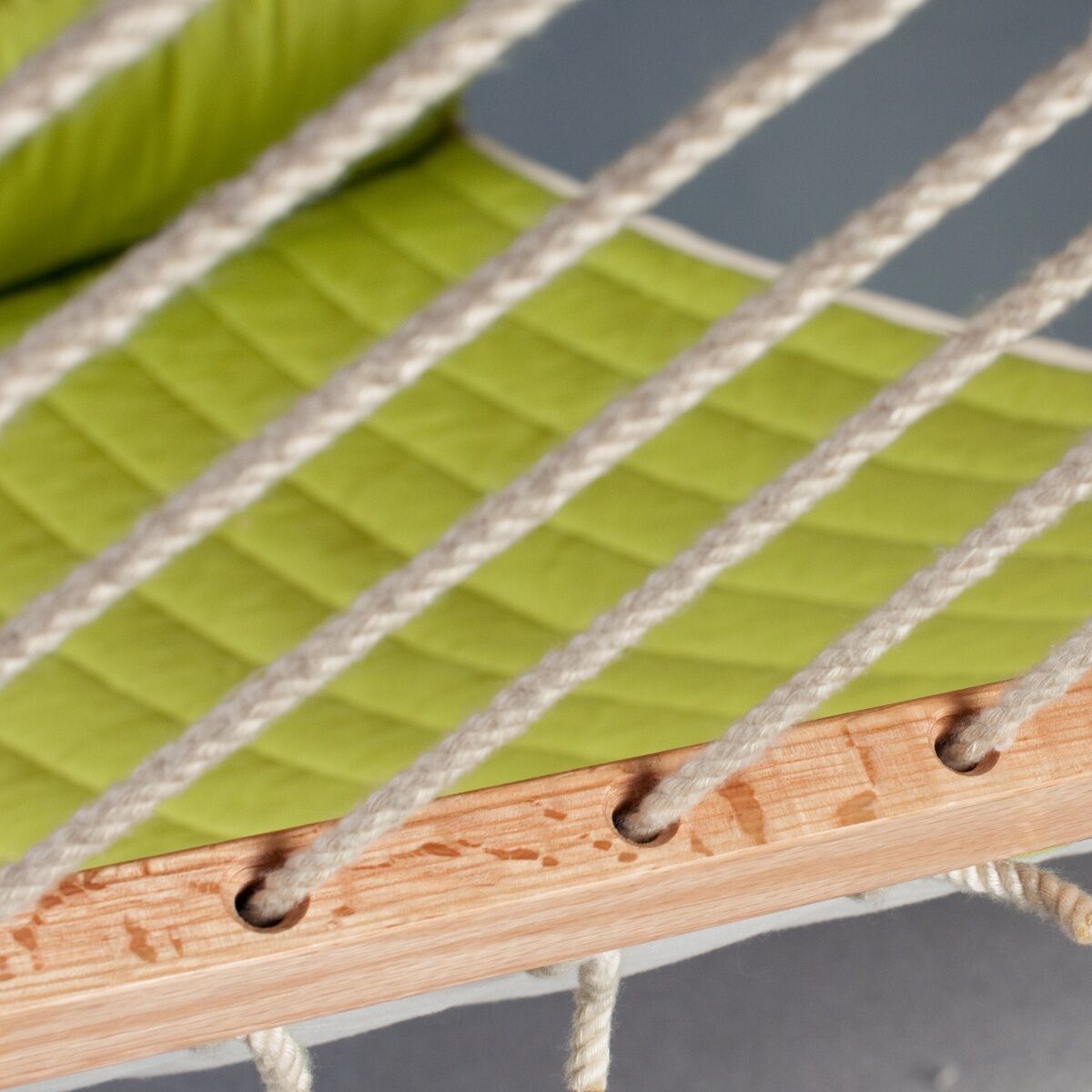 Nahaufnahme einer Hängematte »Alabama« mit grünem gepolstertem Stoff und Holzgestell. Geeignet für den Außeneinsatz, bietet die Hängematte Komfort und Entspannung.