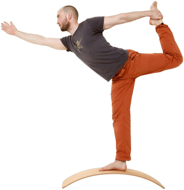 Ein Mann balanciert auf einem geölten Balance Board namens »das.Brett«. Er führt eine Yoga-Übung durch und steht auf einem Bein, wobei er eine Hand nach vorne streckt und die andere am hinteren Fuß hält. Hintergrund ist weiß.