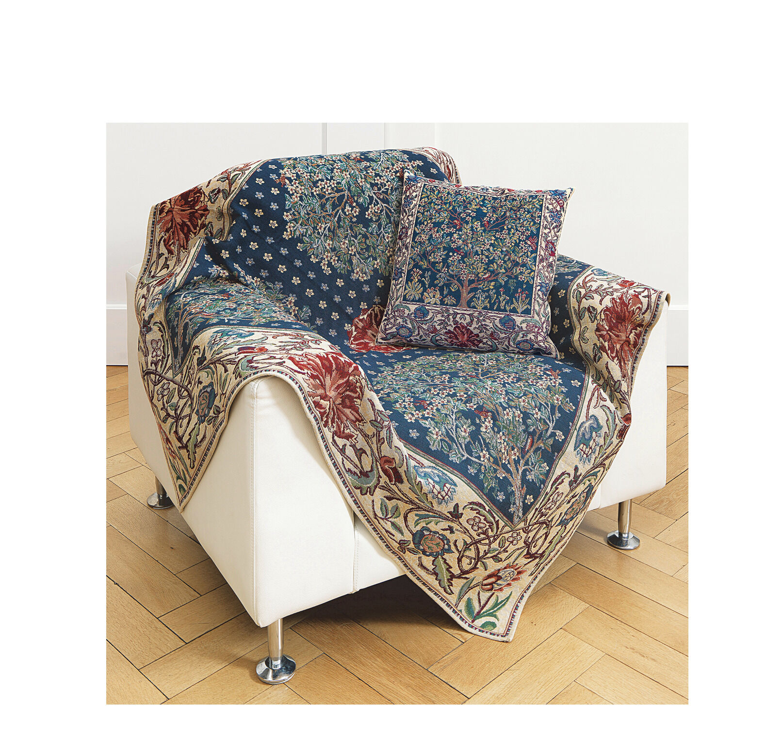 Ein weißes Sofa ist mit einem farbenfrohen Wohnplaid und einer passenden Kissenhülle dekoriert, beide mit einem floralen Muster im Stil von William Morris und dem Motiv 'Baum des Lebens'. Das Design ist in Blau, Rot, Grün, Weiß und Beige gehalten.