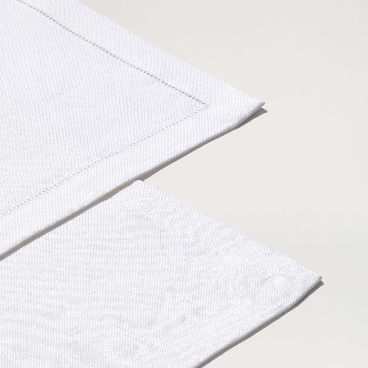 Schlichter, rechteckiger Leinen-Tischläufer in Weiß, auf einem hellen Untergrund ausgebreitet. Die feine Webstruktur und der dezente Saum sind gut sichtbar. Das Produkt wirkt hochwertig und minimalistisch, ideal als elegante Tischdekoration für festliche Anlässe, Familienfeiern oder den täglichen Gebrauch.