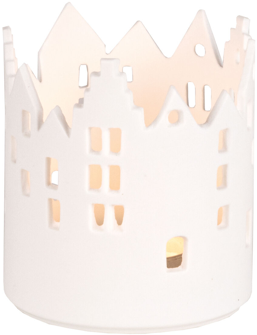 Ein weißes Windlicht mit einer stadtähnlichen Silhouette. Das Windlicht besteht aus Porzellan und hat ausgeschnittene Fensterformen, durch die das Licht einer Kerze scheint.