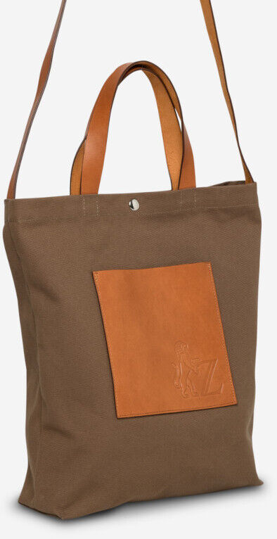Bild einer braunen Jubiläums-Shopper Tasche vom ZEIT Shop mit langen, verstellbaren Lederriemen und Kordel. Die Tasche hat eine quadratische Leder-Außentasche und wird gezeigt in stehender Position mit Vorderansicht.