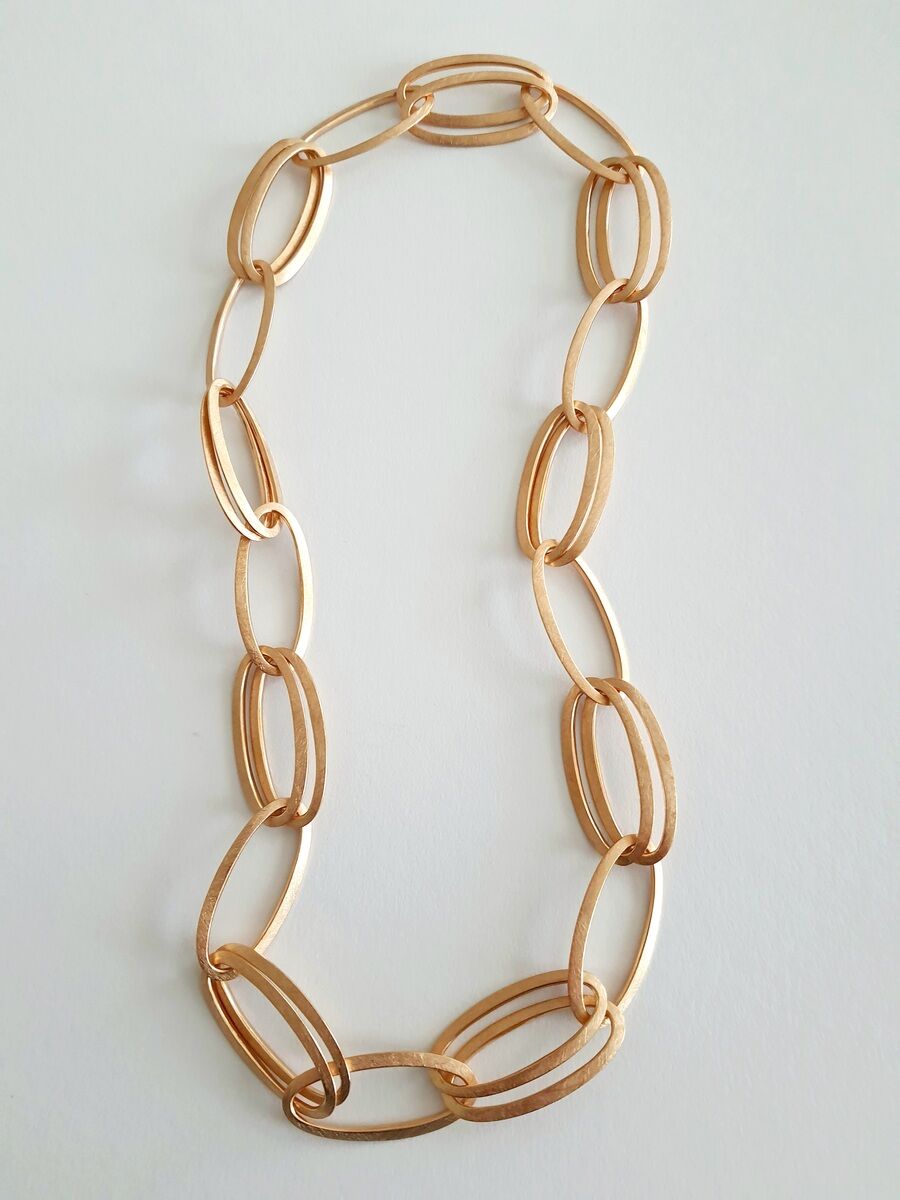 Bild einer goldenen Halskette mit ovalen Gliedern, die elegant auf einem weißen Hintergrund liegt.