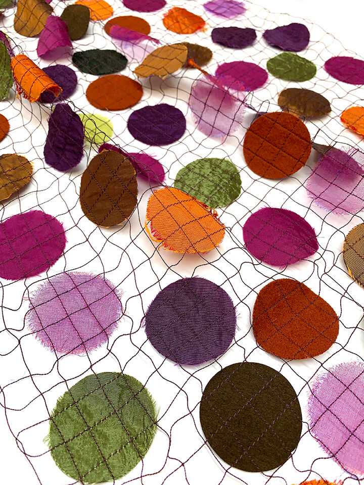 Transparenter Schal mit großen Punkten in verschiedenen warmen Gewürztönen wie Orange, Grün, Purpur, Braun, Rosa und Weinrot. Die Punkte sind auf einem Netzstoff verteilt. Der Schal eignet sich gut als modisches Accessoire für verschiedene Anlässe und Jahreszeiten.