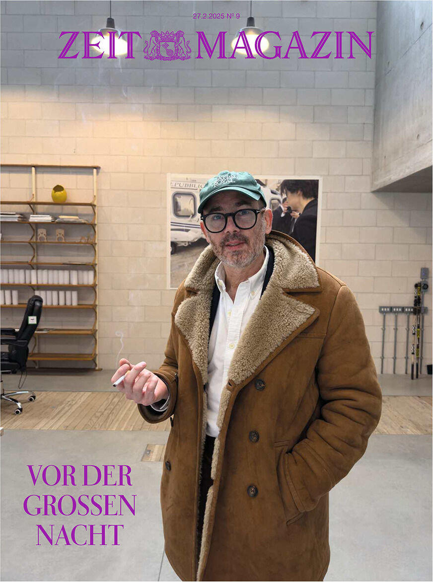 Titelbild des ZEIT Magazins, Ausgabe 9/2025. Ein Mann in einem beigen Mantel und blauer Mütze steht in einem modern eingerichteten Raum und schaut in die Kamera. Der Text 'Vor der Großen Nacht' ist unten im Bild sichtbar.
