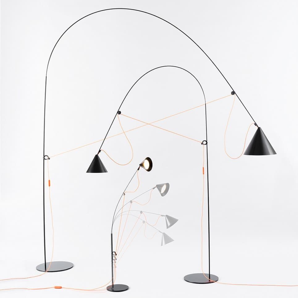 Bild der Tischlampe AYNO mit mehreren flexiblen, schwarzen Armaturen und orangefarbenen Kabeln, die in verschiedenen Winkeln eingestellt sind, vor einem weißen Hintergrund.