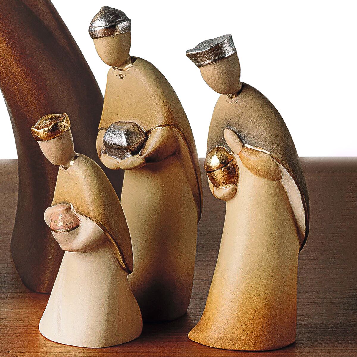 Das Bild zeigt detailreiche, stilisierte Figuren einer 12-teiligen Weihnachtskrippe »Stern von Bethlehem«. Die aus unbehandeltem und farbigen Holz gefertigten Figuren stellen die Heilige Familie und weitere Beteiligte der Weihnachtsgeschichte dar. Das Design ist schlicht und modern, die Figuren tragen traditionelle Umhänge und Mützen. Im Hintergrund ist ein abstrahierter Stern zu sehen, der auf den Stern von Bethlehem verweist.