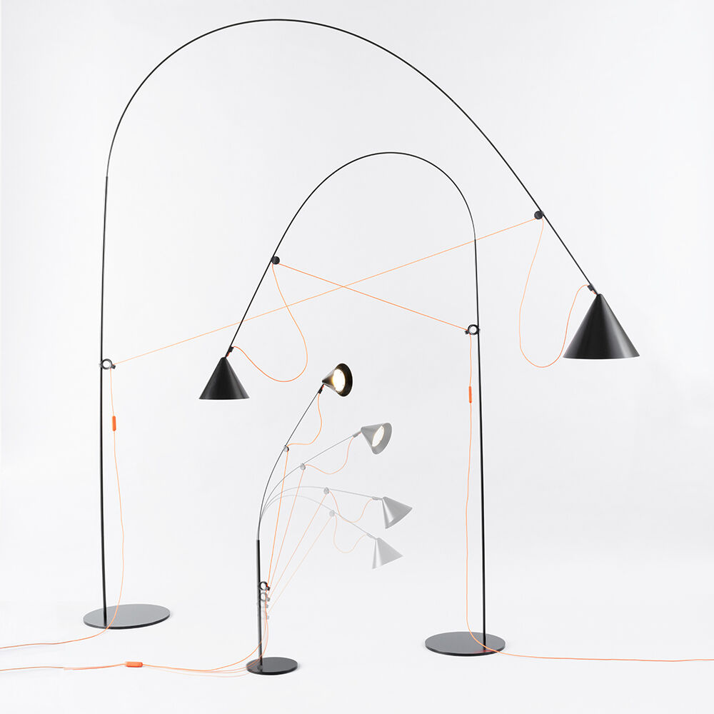 Eine moderne Tischlampe namens 'AYNO' mit schwarzem Metallgestell und orangefarbenem Kabel, in einem minimalistischen Design. Die Lampe ist verstellbar und elegant, ideal für zeitgenössisches Innendesign.