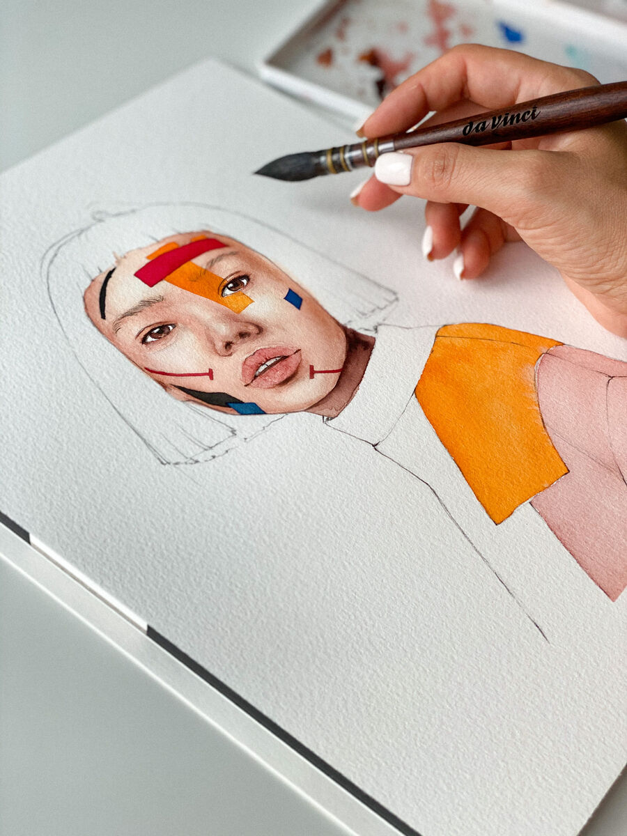 Ein traditioneller Aquarellpinsel mit Ethergraf®-Metallspitze wird verwendet, um ein Porträt zu malen. Die Zeichnung zeigt eine Frau mit bunten Farben im Gesicht. Im Hintergrund sind Aquarellfarben sichtbar. Der Pinsel hat eine Holzgriff mit einer Metallkappe.