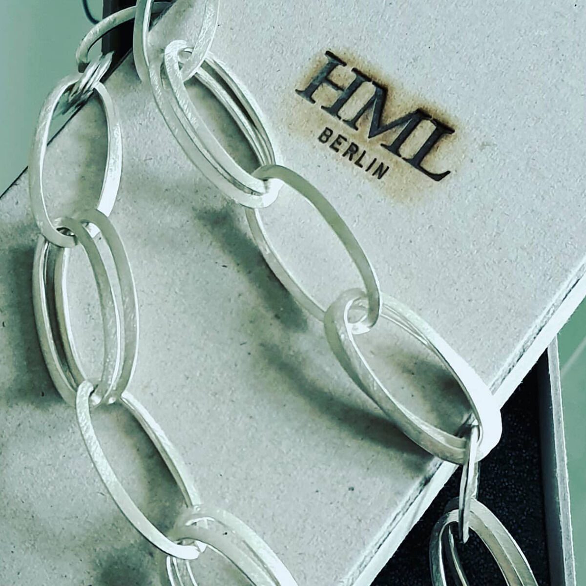 Detailaufnahme des handgefertigten Colliers »GRACE« aus 925er Silber von HML Berlin. Die Schmuckkette mit großen, ovalen Gliedern liegt auf einer edlen, hellgrauen Schmuckschachtel mit dem Aufdruck 'HML BERLIN'. Zeitloses, puristisches Design, hochwertig verarbeitet.