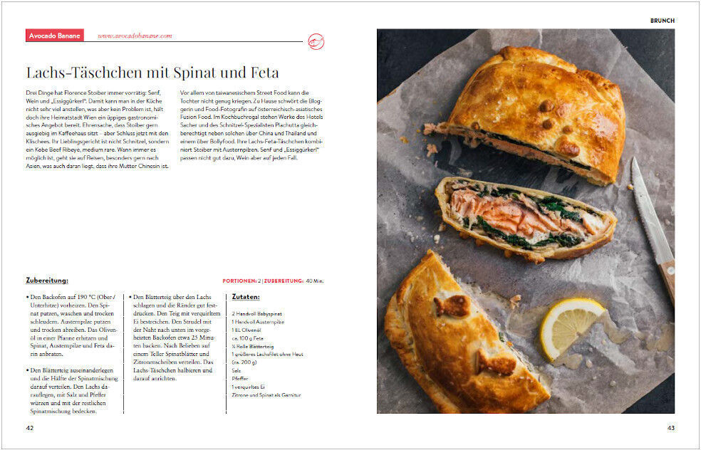 Doppelseite eines Kochbuchs mit Rezept und Foto. Links steht ein Rezept für Lachs-Taschen mit Spinat und Feta. Rechts ist ein Foto der fertigen Lachs-Tasche, teilweise aufgeschnitten, auf Backpapier mit einer Zitronenscheibe und einer Gabel.