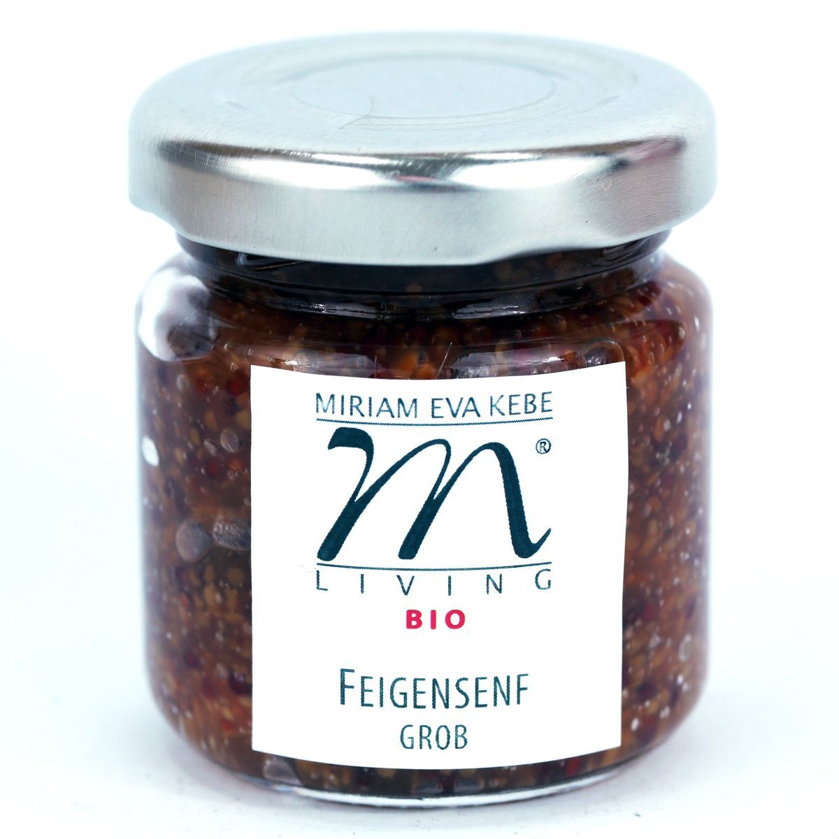 Ein Glas grober Bio-Feigensenf der Marke Kebe Living mit silbernem Metalldeckel. Das Glas ist gefüllt mit dunkelbraunem, körnigem Senf, das weiße Etikett trägt ein stilisiertes M-Logo sowie die Produkt- und Markenbezeichnung. Das Design wirkt hochwertig und handwerklich.