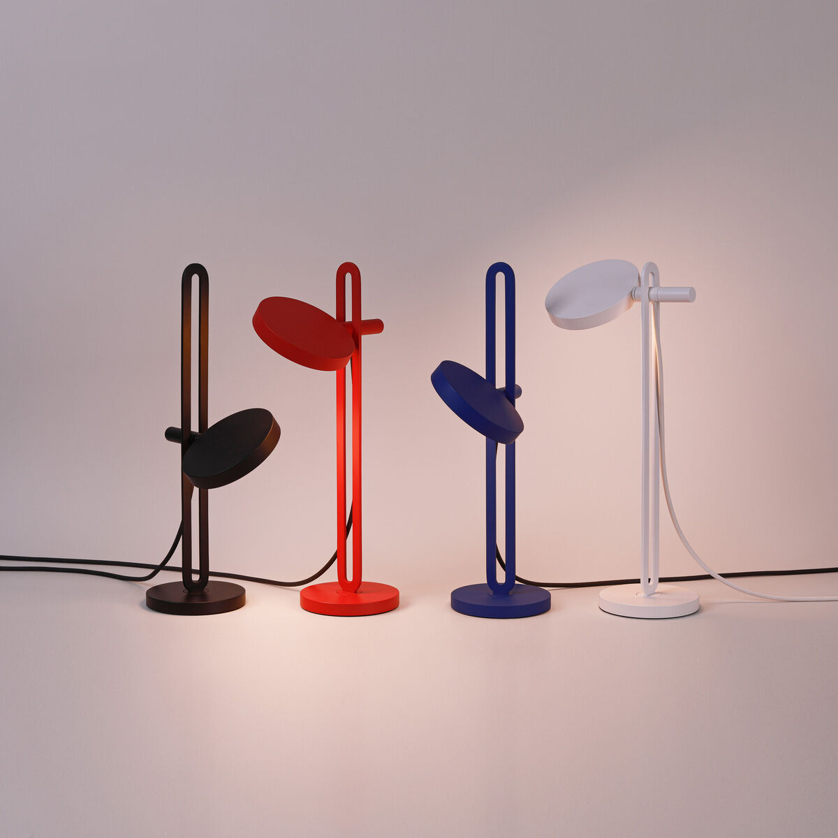 Eine Reihe von vier modernen Tischlampen der Marke »Echo« in den Farben Schwarz, Rot, Blau und Weiß. Jede Lampe hat ein minimalistisches Design mit einem ovalen Kopf und einer schlanken Basis. Perfekt für stilvolle Innenbeleuchtung.