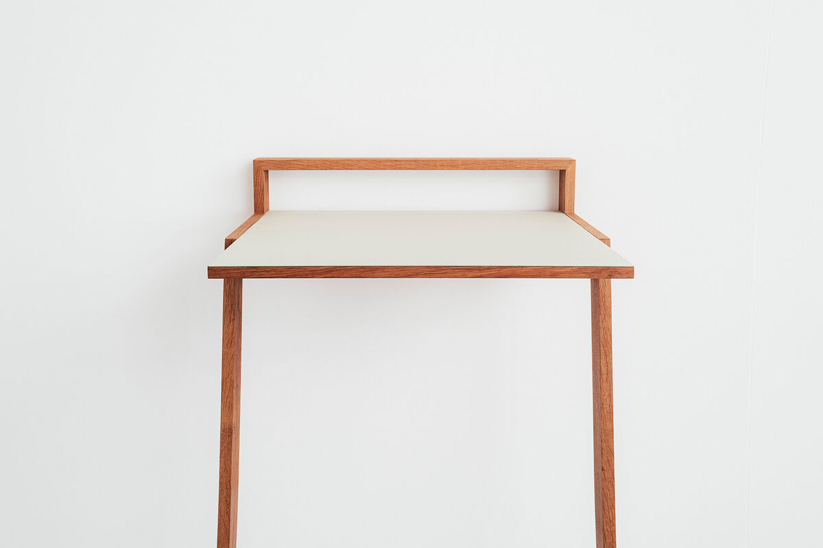 Ein minimalistisches und modernes Stehpult, genannt »buckowski«, hauptsächlich aus Holz gefertigt. Es hat eine weiße Arbeitsfläche und braune Beine und Struktur. Das Design ist schlicht und elegant, ideal für Büros oder Home Office.