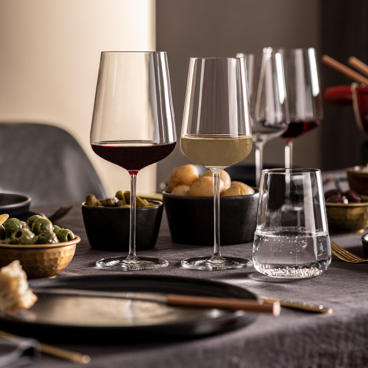 Ein Arrangement von hochwertigen Weingläsern aus dem Sommelier-Bundle »Vervino« auf einem elegant gedeckten Tisch. Verschiedene gefüllte Gläser mit Rot- und Weißwein, umgeben von Schalen mit Snacks.