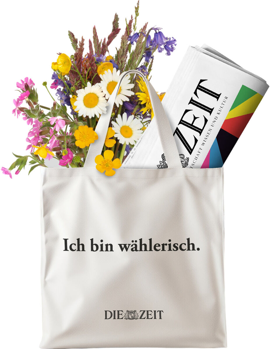 Eine beige Stofftasche mit der Aufschrift 'Ich bin wählerisch', gefüllt mit verschiedenen bunten Blumen und einer gefalteten Zeitung.