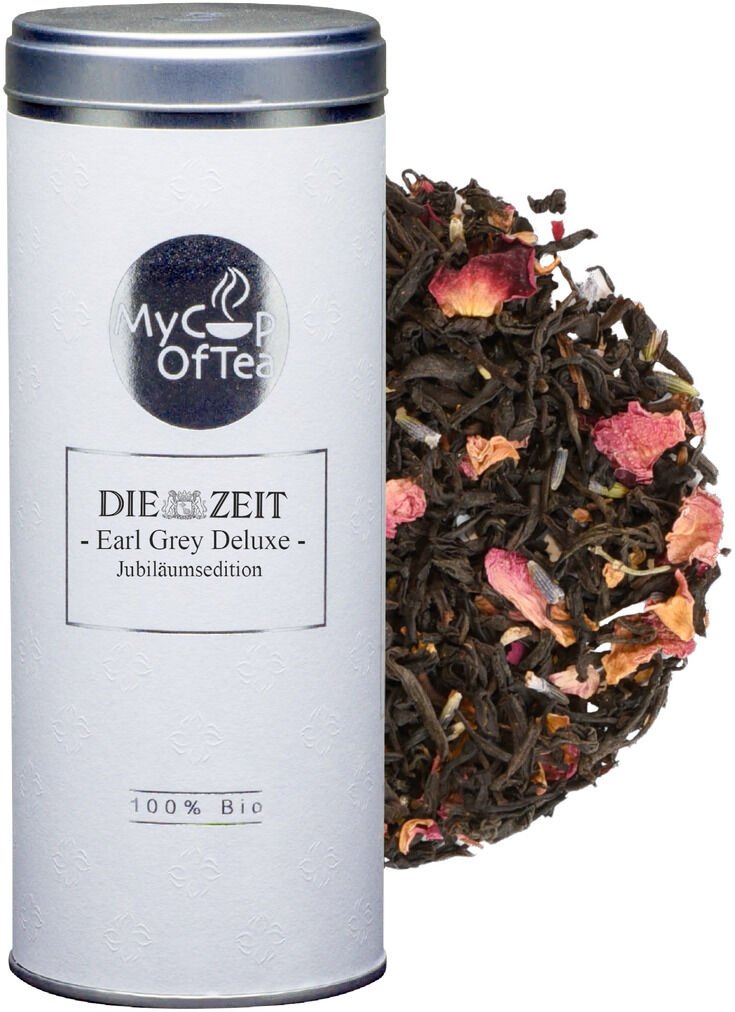 Ein edles Tee-Set der Jubiläumsedition von 'Die Zeit' mit der Aufschrift 'Earl Grey Deluxe 100% Bio' auf einer weißen Dose und losem schwarzem Tee mit rosa Blütenblättern daneben.