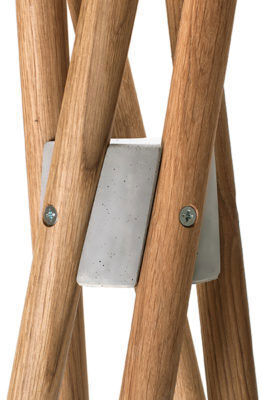 Detailansicht eines modernen Holzdekorationsobjekts. Mehrere helle Holzstäbe sind kunstvoll miteinander verbunden und von einer grauen Metallplakette gehalten. Der Stil ist minimalistisch und elegant.