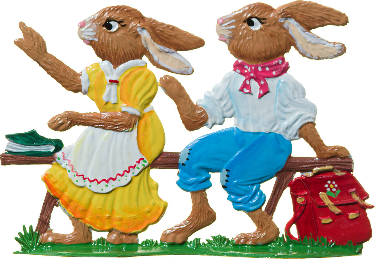 Zinnfigur von Wilhelm Schweizer Zinnmanufaktur: Zwei Hasenkinder auf einer Bank, eines im gelben Kleid mit weißer Schürze, das andere in weiß-blau-roter Kleidung. Kleine Details wie ein Ranzen, Gras und Bücher verstärken die verspielte Frühlingsszene.