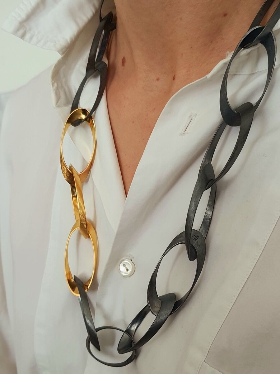 Handgefertigte Halskette 'Standing Ovations' von HML-Collier, gefertigt aus Silber und Gold. Die Kette ist sichtbar an einem Mann in einem weißen Hemd.