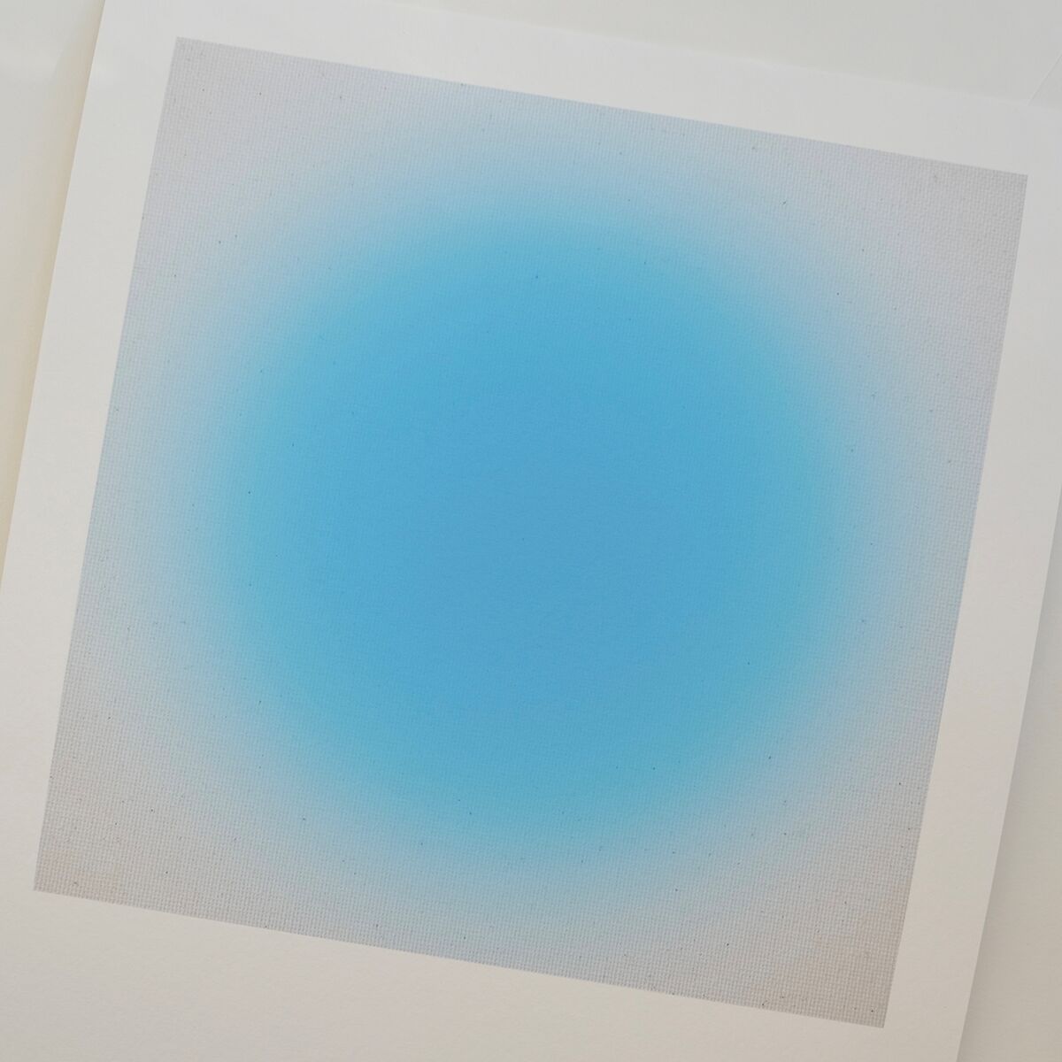 Das Bild zeigt einen hochwertigen Fine-Art-Print der ZEIT-Sonderedition »Sorbet« von Studio Anastasia Benko. Im Zentrum befindet sich ein verlaufender, intensiver blauer Kreis, der sich sanft ins Helle auf weißem, rechteckigem Papier ausdehnt. Das Motiv wirkt minimalistisch und modern.