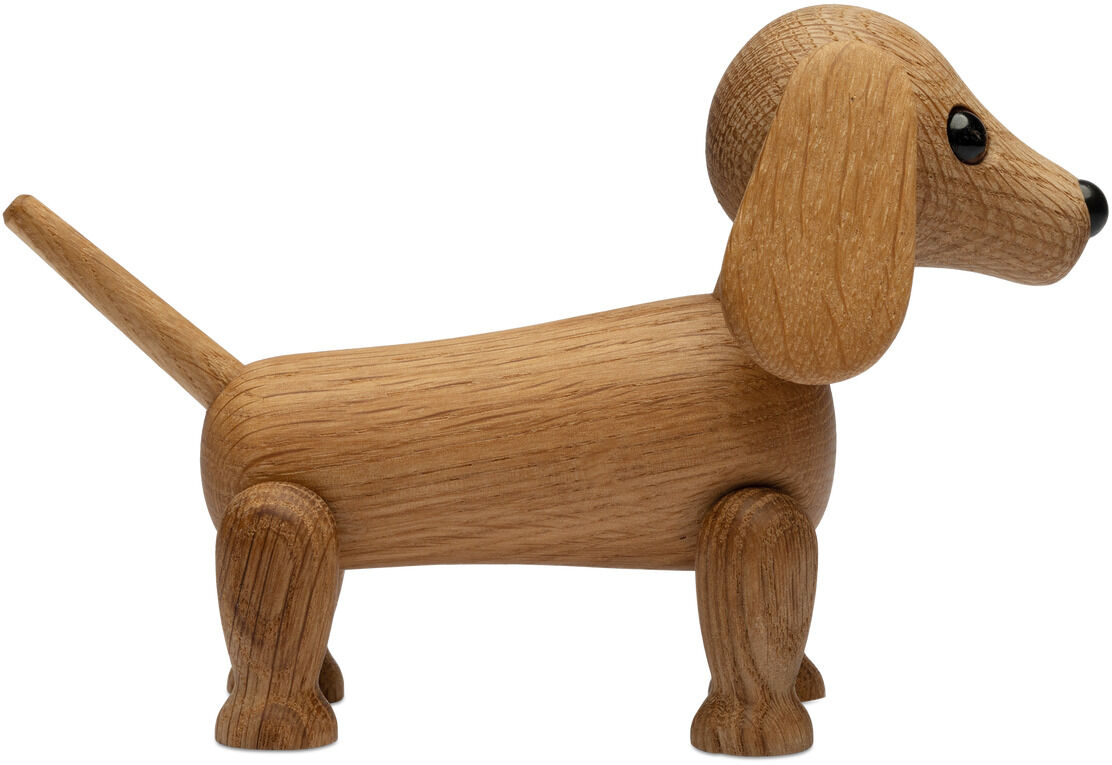 Die Holzfigur »Dackel Amigo« von Spring Copenhagen zeigt einen stilisierten Dackel aus hellem Holz mit langen Ohren, schwarzer Schnauze und schwarzen Augen. Die Oberfläche wirkt glatt und hochwertig verarbeitet, ideales Wohnaccessoire im skandinavischen Designstil.