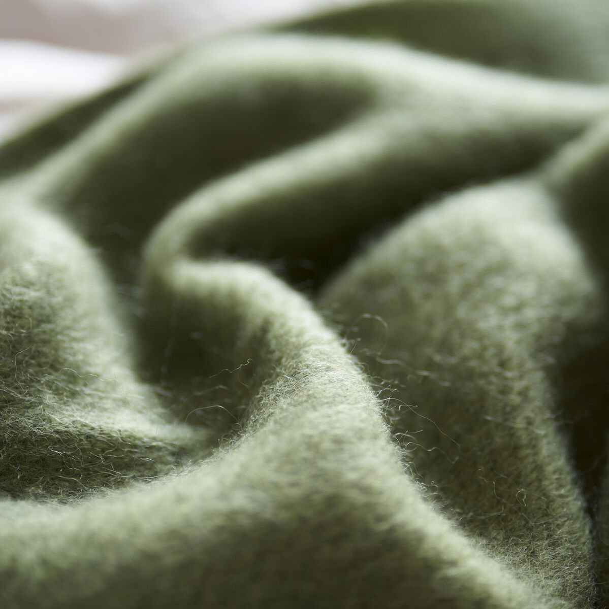 Eine weiche, grüne Decke aus Wolle, die sanft drapiert ist.
