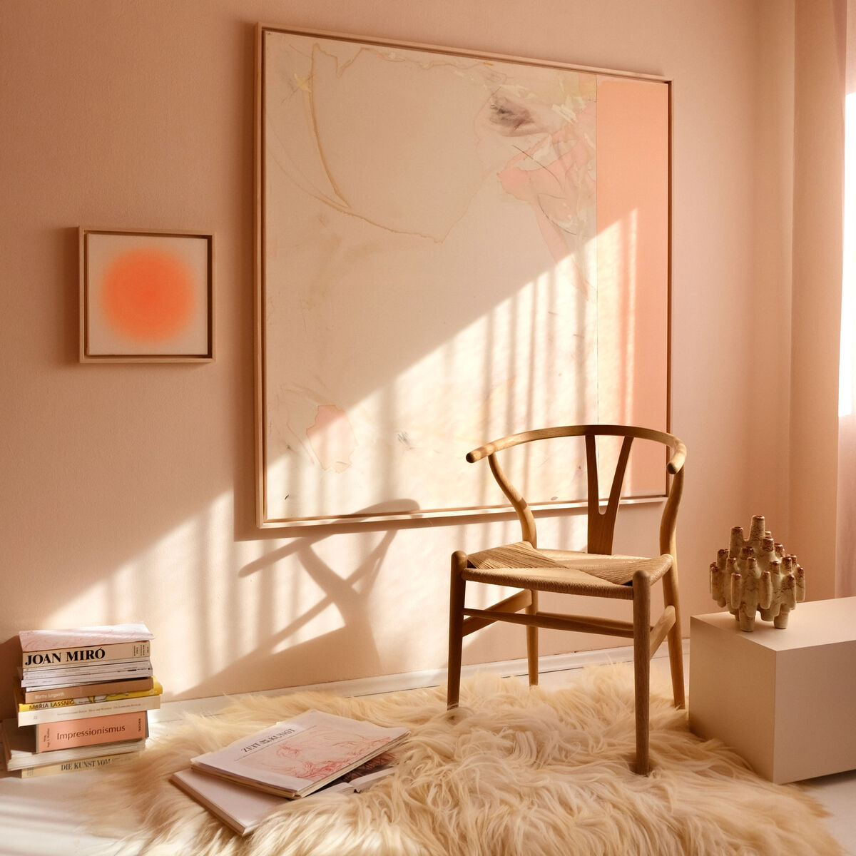 Modern eingerichtetes Zimmer mit einer abstrakten Kunstedition an der Wand in warmen Pastelltönen, einem Holzstuhl, hellem Teppich und Sonnenstrahlen, die durch das Fenster fallen. Einladende und ruhige Atmosphäre mit dekorativen Details.