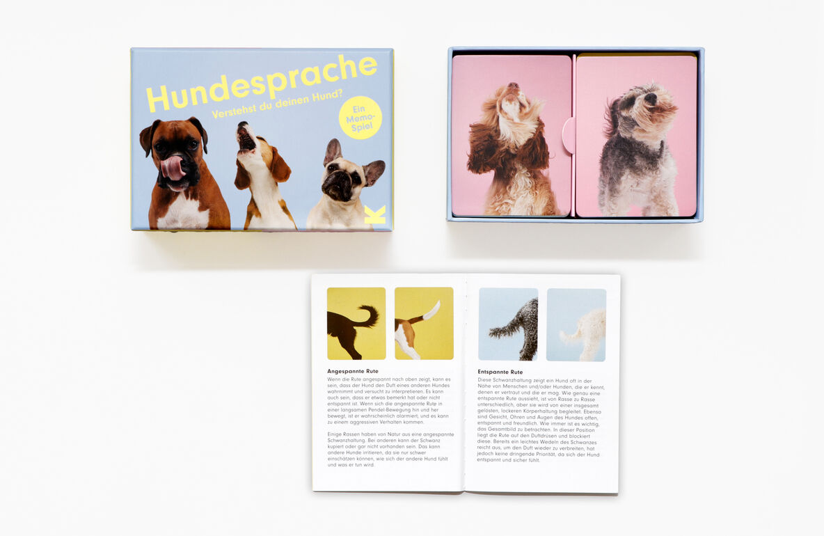 Das Bild zeigt ein Memo-Spiel mit dem Titel „Hundesprache - Verstehst du deinen Hund?“. Links ist die Verpackung mit Hundebildern und dem Titel in gelber Schrift zu sehen. Rechts oben sind zwei geöffnete Kärtchen mit Hundebildern und unten ein Heft mit erklärenden Texten und Abbildungen von Hunden.