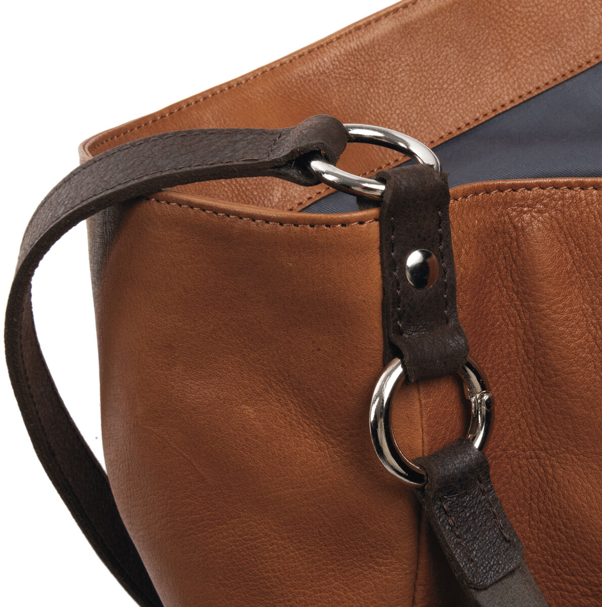 Nahaufnahme einer braunen Lederbeuteltasche »Chaza Pouch Upend« mit dunkelbraunen und grauen Details sowie silbernen Metalringen.
