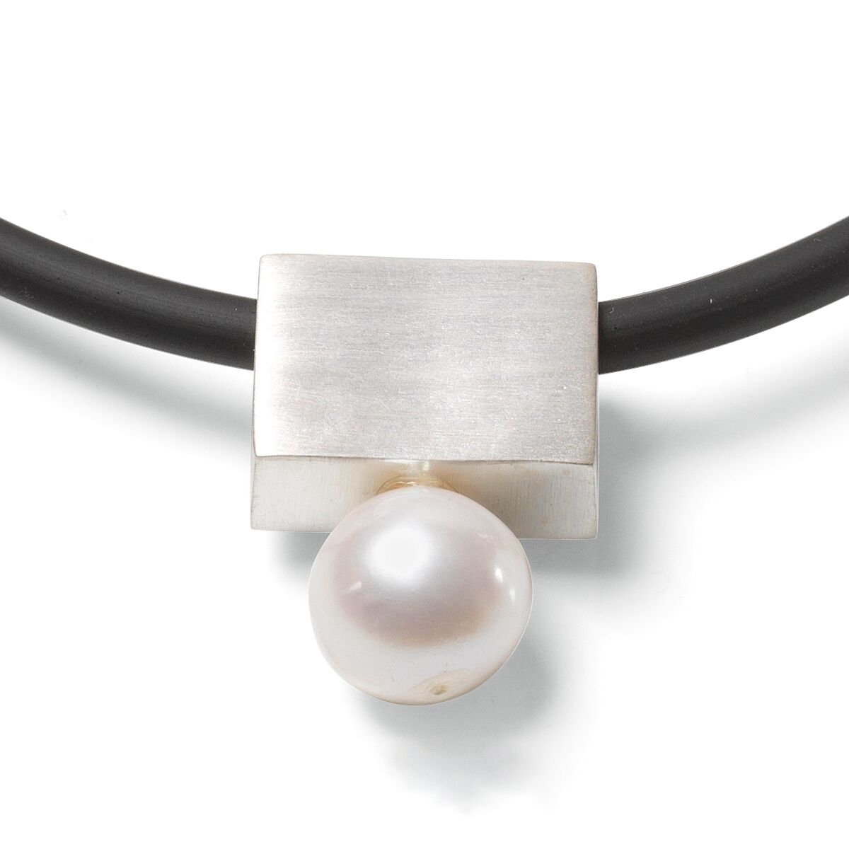Nahaufnahme eines eleganten Colliers aus schwarzem Kautschuk mit rechteckigem Anhänger aus versilbertem Messing und weißer Süßwasserperle. Der Schmuck hat klare, minimalistische Formen und wirkt modern und stilvoll.