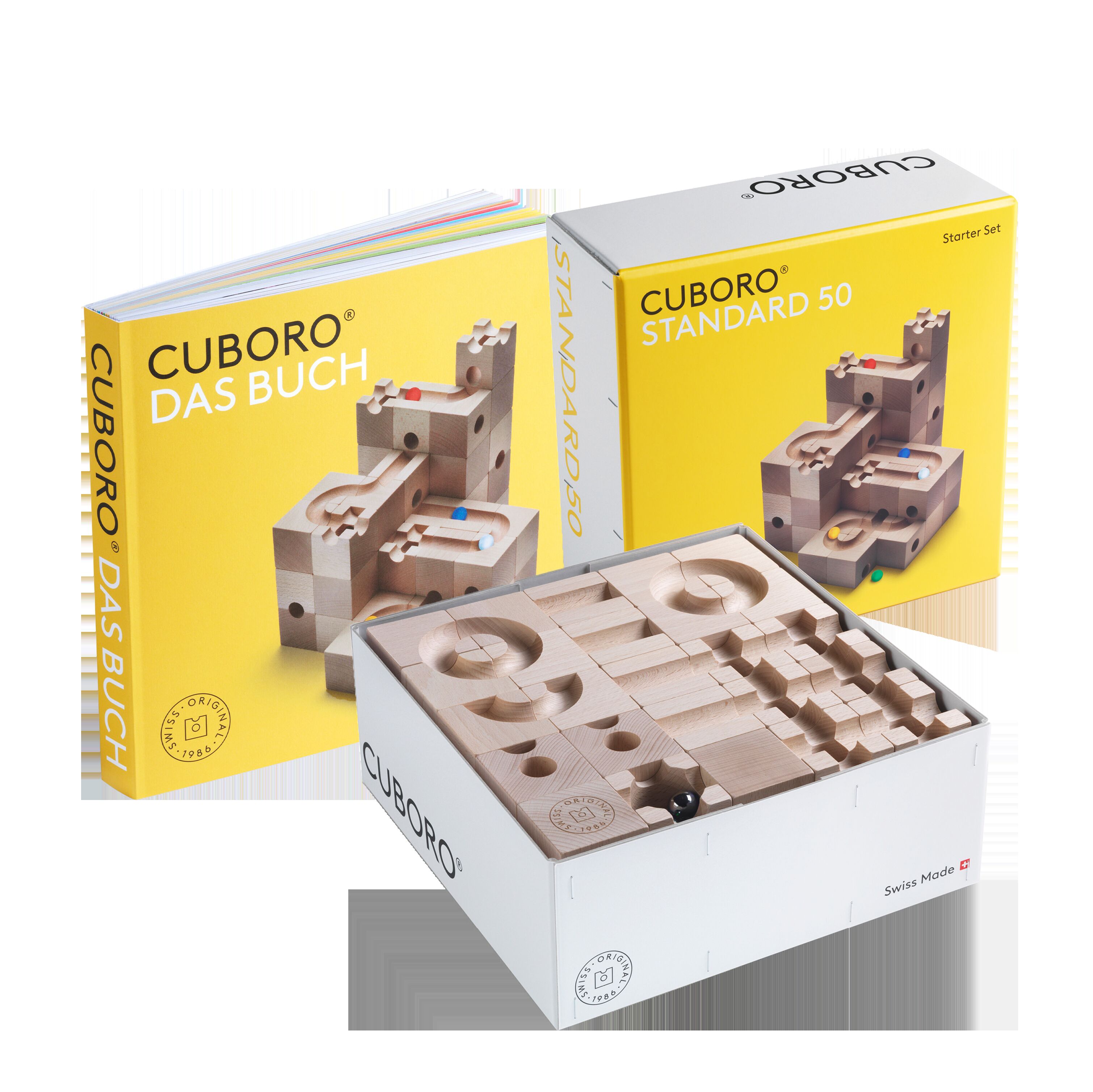 Zu sehen ist das CUBORO Set »STANDARD 50 & DAS BUCH« von Cuboro. Die Verpackung und das geöffnete Set zeigen naturbelassene Holzwürfel für eine Kugelbahn. Daneben steht das dazugehörige Buch mit gelbem Cover, auf dem Kugelbahnbeispiele abgebildet sind.